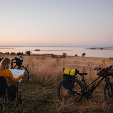 Kvinne titter på et kart mens hun sitter ved sitt telt underveis på en sykkelferie i Danmark