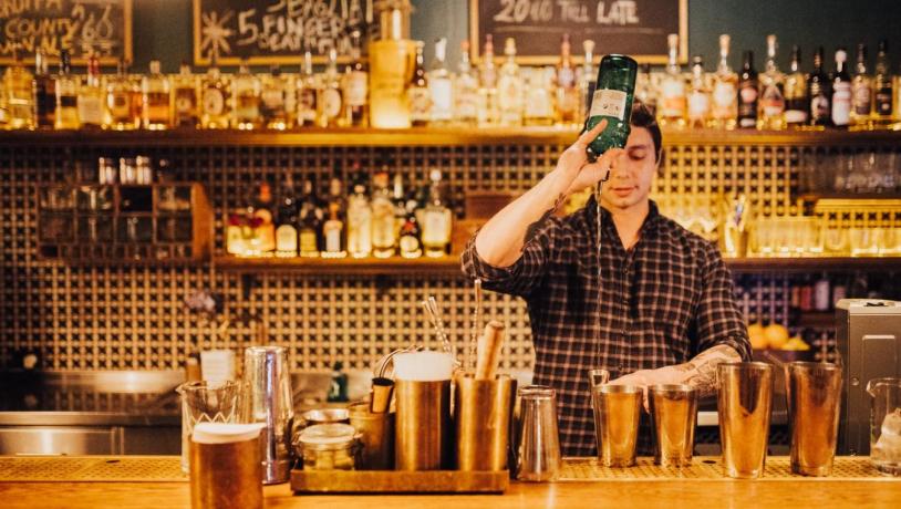 bartender mikser cocktails ved baren Lidkoeb i København, Danmark