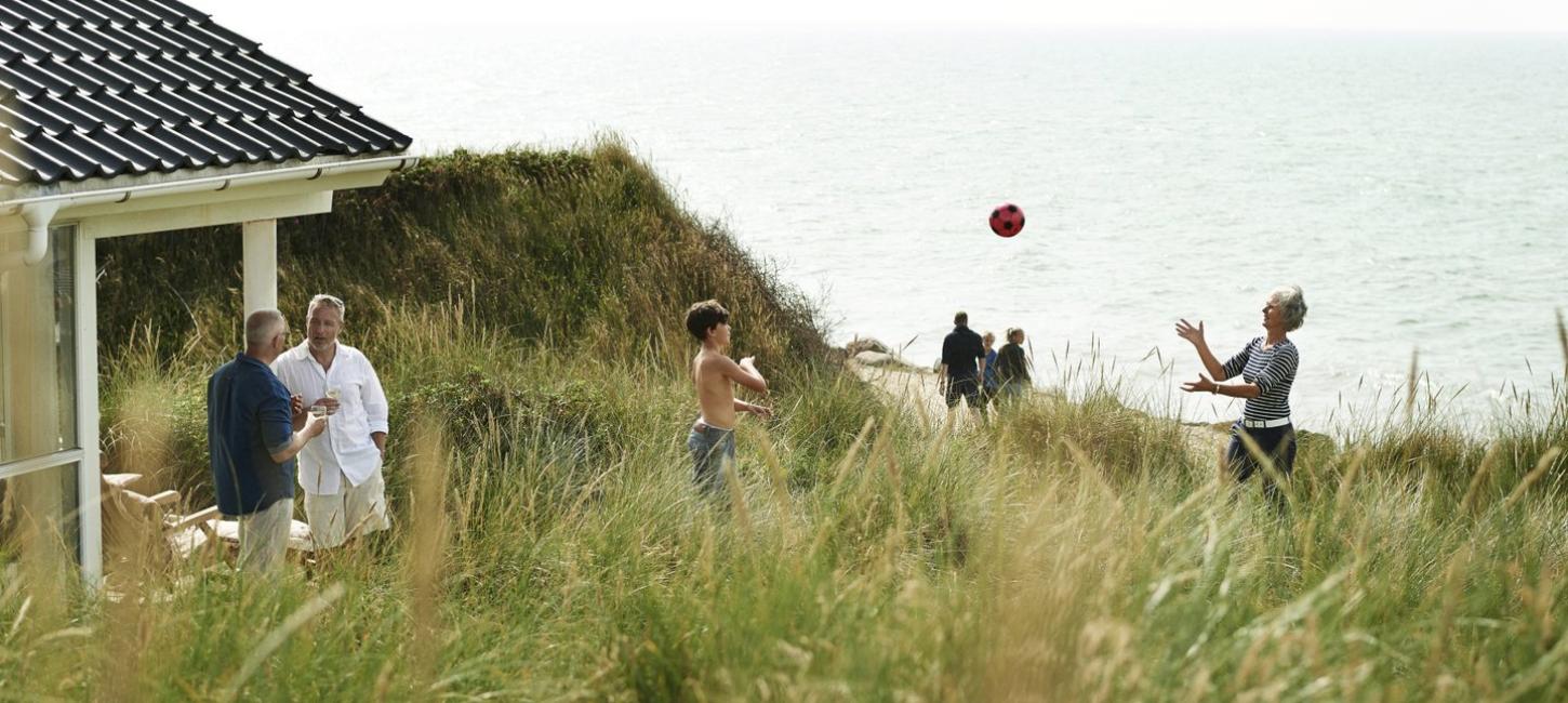 Familie som leker ved feriehuset i Jylland