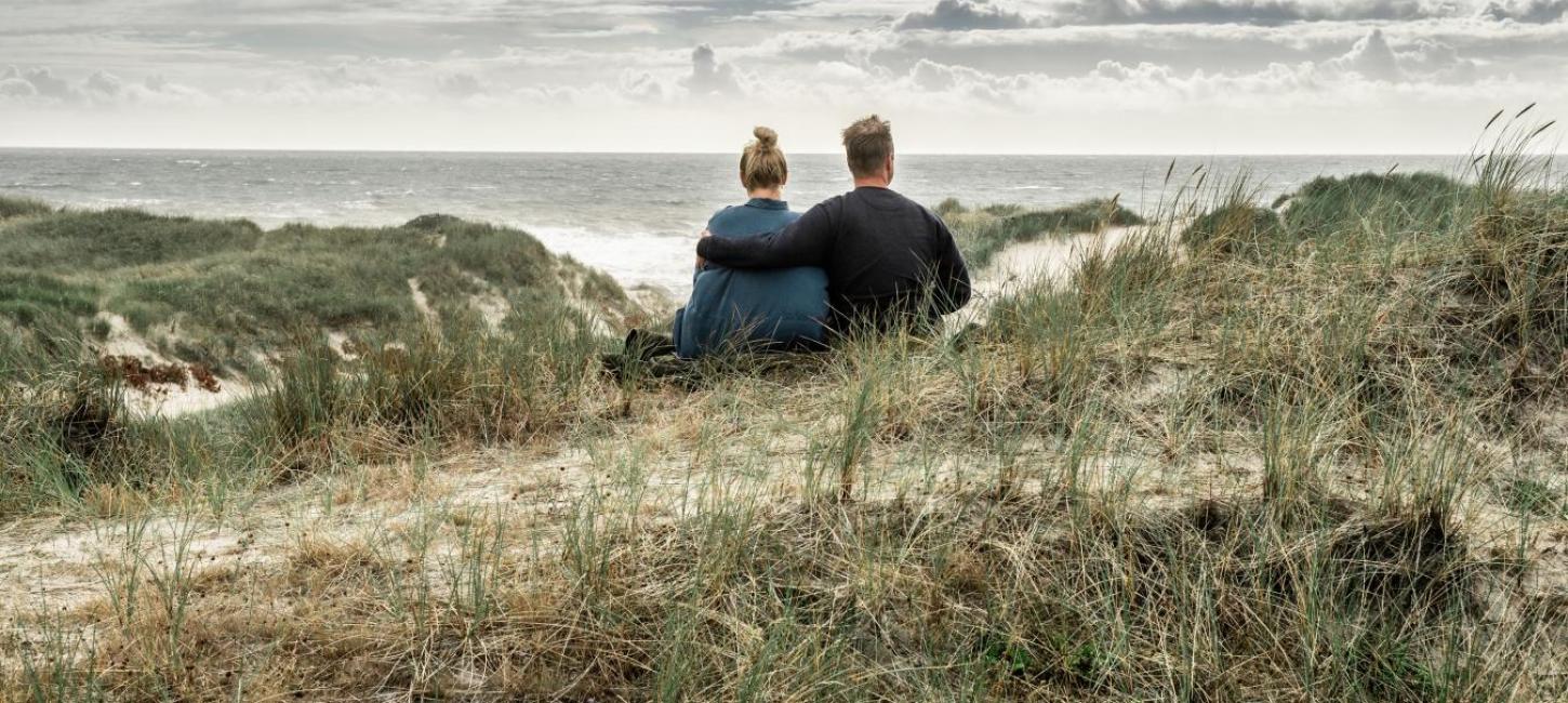 Couple sitting in dunes at West coast, West Jutland