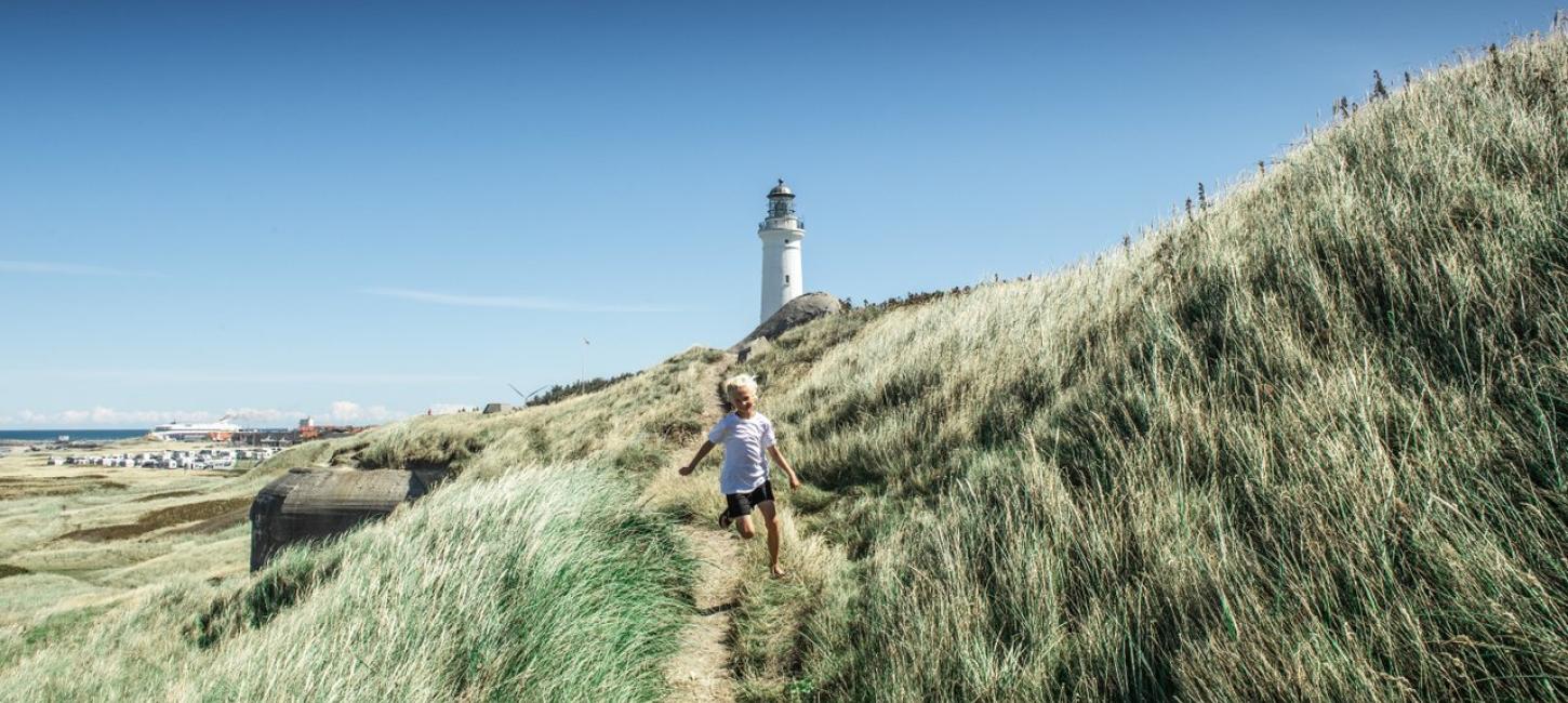 Gutt som løper i gresset ved Hirtshals fyr
