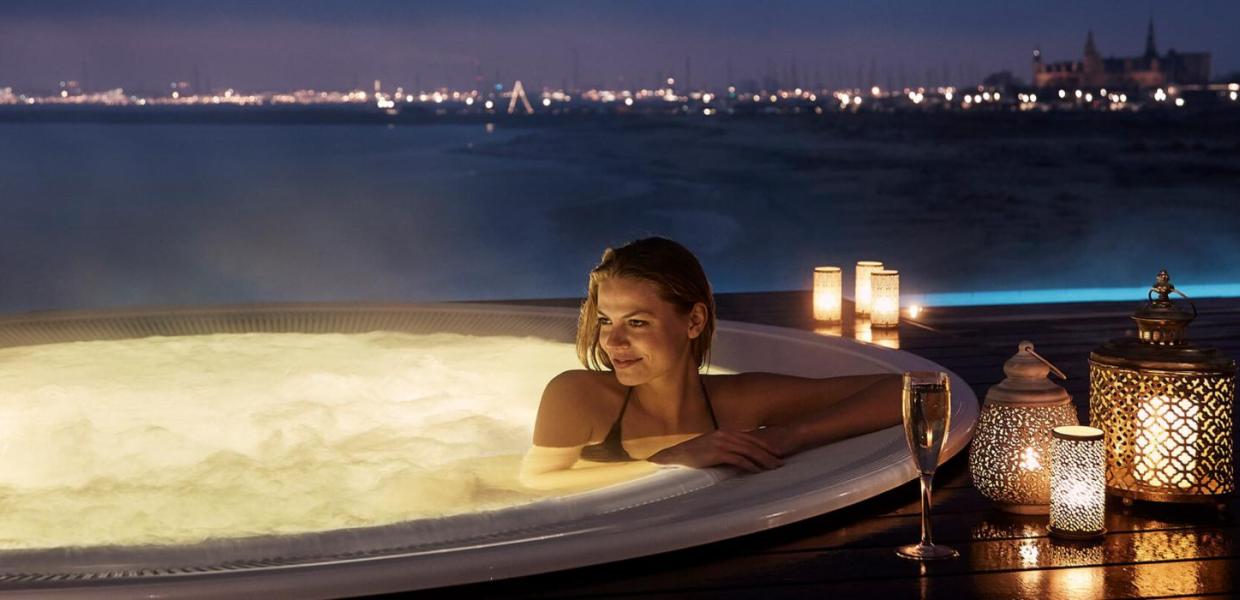 Woman sitting in a hot tub overlooking the sea at Marienlyst Beach Hotel in North Zealand, Denmark
