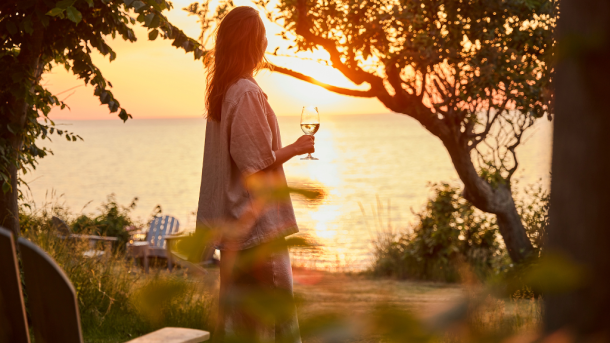 Kvinne med vinglass i solnedgang ved Helenekilde badehotel