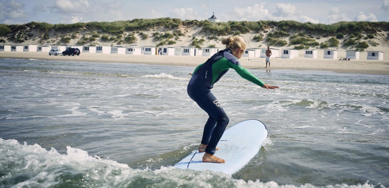 Jente som surfer på Løkken strand