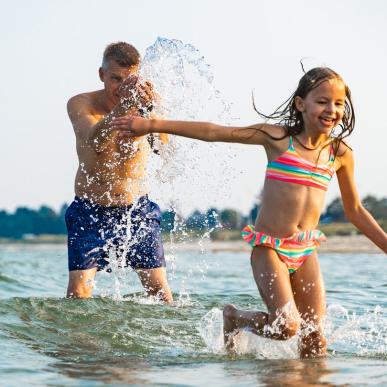 Far og datter leker i vannet ved Saksild Strand, Kystlandet, Danmark