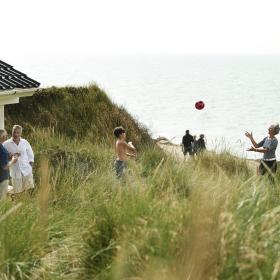 Familie som leker ved feriehuset i Jylland