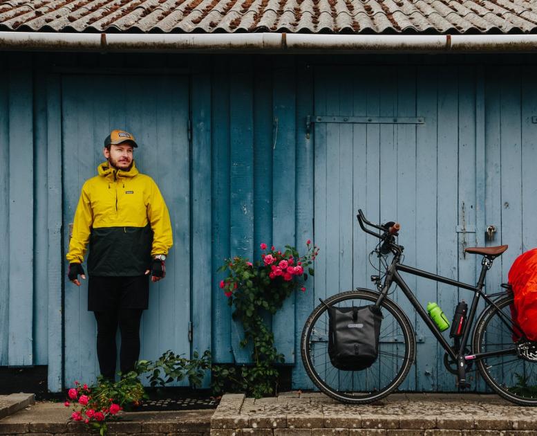 Mann mit gepacktem Fahrrad vor einem Haus auf dem Dänischen Ostseeradweg in Südjütland