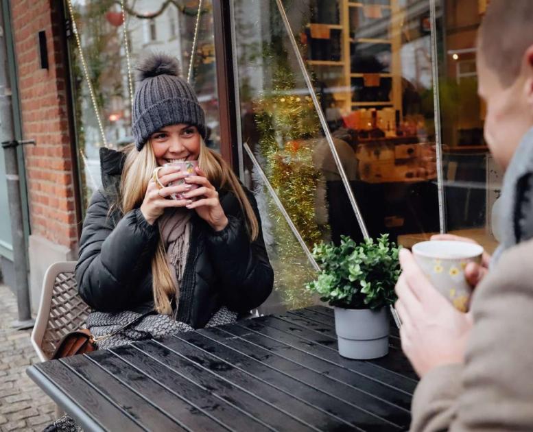 Par nyter en kopp kaffe utenfor en kafe i Aalborg, Danmark