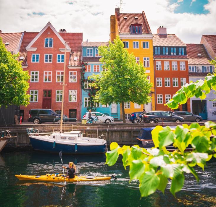 Woman kayaking past coloured houses in Christianshavn